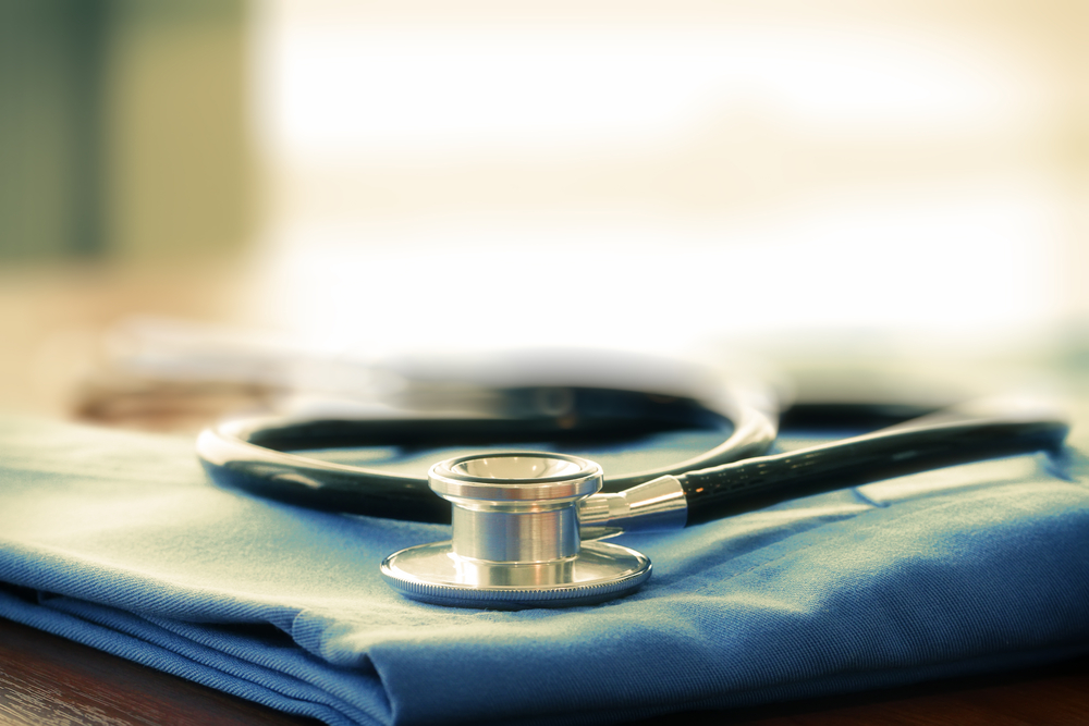Stethoscope with blue doctor coat on wooden table with shallow DOF evenly matched and background Stethoscope with blue doctor coat on wooden table with shallow DOF evenly matched and background